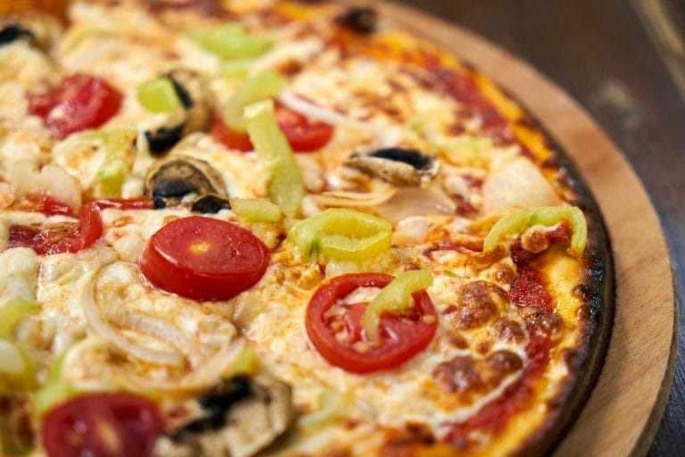 Close-up of a freshly baked Italian pizza topped with vibrant vegetables and cheese.